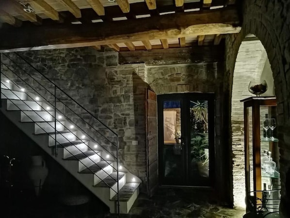 A stone staircase with modern lighting, leading to a door with a glass panel.