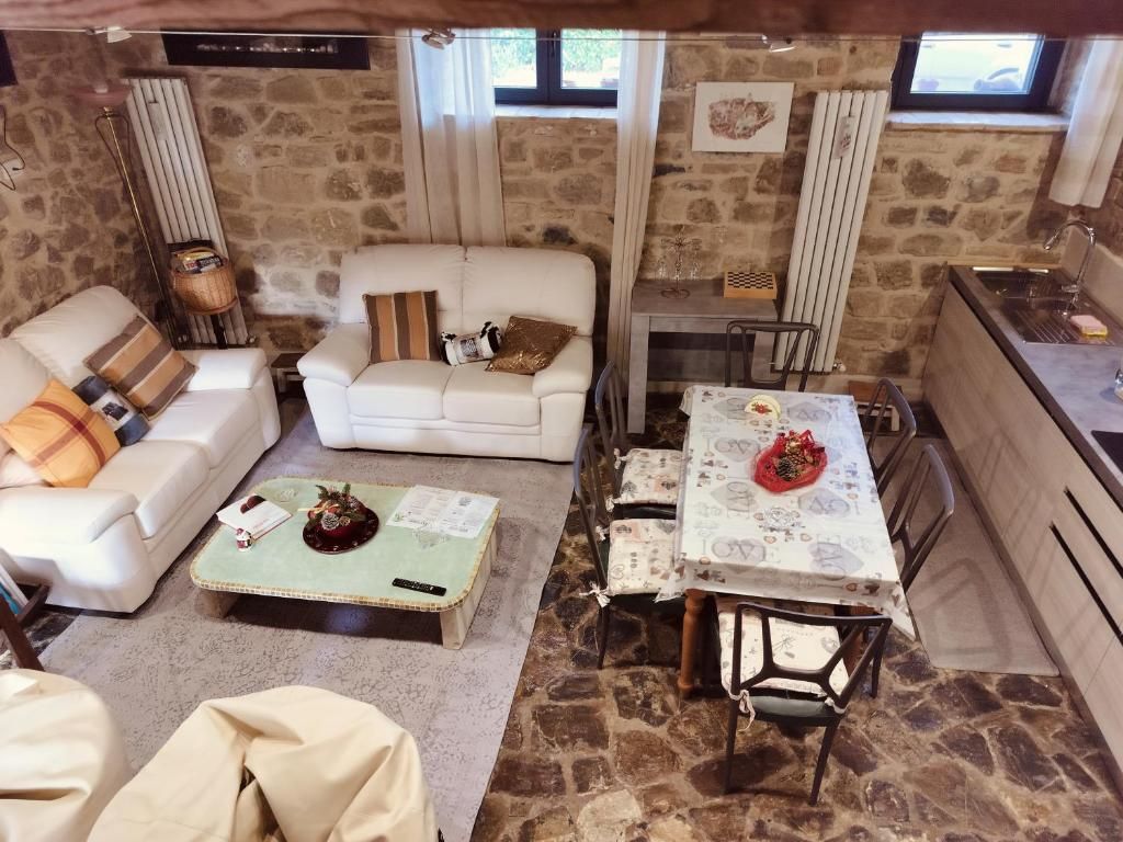 A cozy living room with a stone wall, a white sofa, a coffee table, and a dining table with chairs.