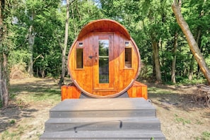 A wooden cabin with a circular door, set in a forest. - Carriage House King Suite near Battlefield - Patio, Hot Tub, Sauna (Gettysburg)