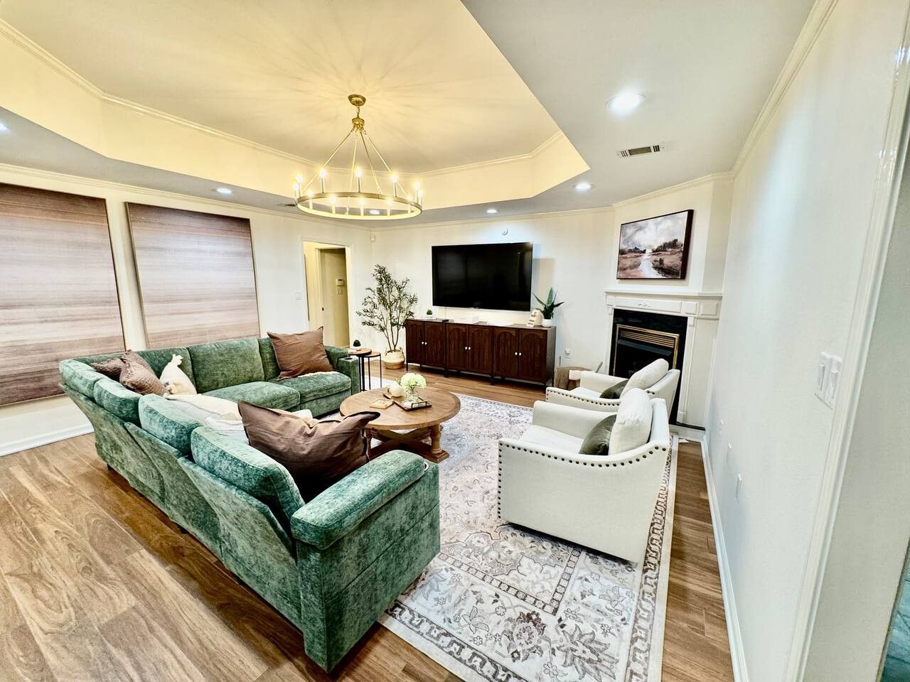 A modern living room with a sectional sofa, a white armchair, a coffee table, and a flat-screen TV.