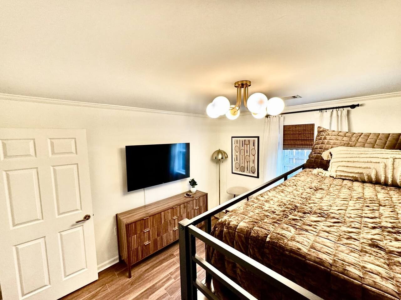 A bedroom with a bed, a TV, a cabinet, and a ceiling light fixture.