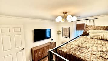 A bedroom with a bed, a TV, a cabinet, and a ceiling light fixture.