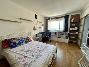 Ein Schlafzimmer mit Bett, Schreibtisch und Regalelement.