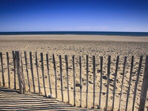 Een strand met een houten omheining en een gestreepte strandmat.