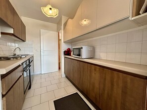 A compact kitchen with a microwave, a sink, and wooden cabinets. - T3 apartment, parking, sea view - 6 guests (Canet-en-Roussillon)