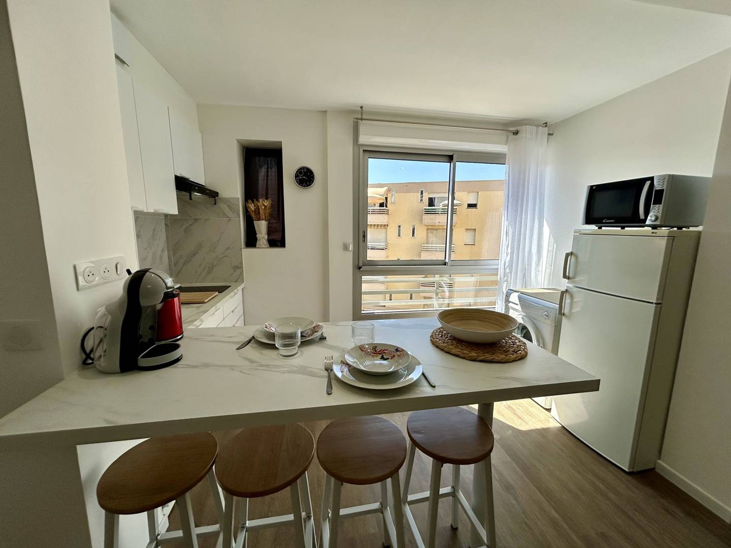 Une cuisine moderne dotée d’un îlot central, de tabourets de bar, d’un four à micro-ondes et d’un réfrigérateur.