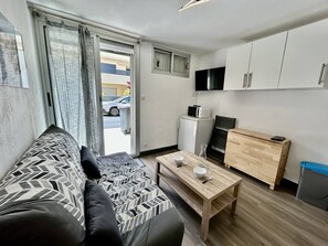 Ein gemütlicher Wohnraum mit Sofa, Esstisch, Küchenzeile und einer Glastür zum Außenbereich.