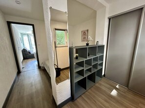 Ein Korridor mit Holzboden, einem grauen Regalschrank und einer Schiebetür.