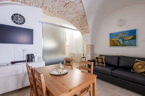 Eine moderne Küche mit Esstisch und Stühlen, einer schwarzen Couch und einem Gemälde an der Wand.