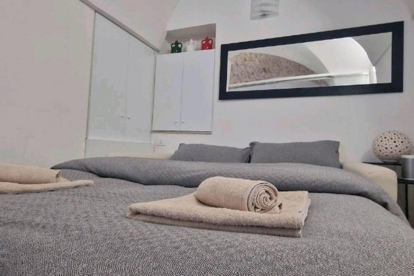 Une chambre à coucher avec un grand lit, un miroir et une armoire.