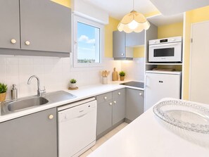 A modern kitchen with grey cabinets, a dishwasher, a microwave, and a sink. - Spacious apartment with sea view - 7 guests (Canet-en-Roussillon)