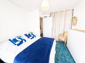 Ein Hotelzimmer mit Bett, Stuhl, Schrank und einer Badezimmertür.