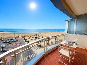 Ein Balkon mit Blick auf einen Strand und einen Parkplatz.