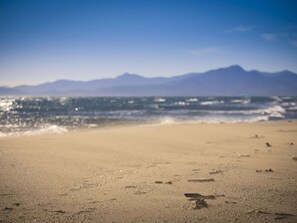 Ein Strand mit Fußabdrücken und einer Bergkette im Hintergrund.