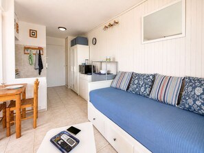A compact room with a bed, a small table, and a kitchenette area. - Studio sea view, AC, pets allowed - 2 guests (Canet-en-Roussillon)