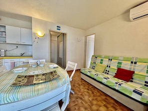Espaço compacto com mesa de jantar, cadeiras, sofá e cozinha compacta.