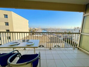 Ein Balkon mit einem Tisch für zwei Personen, mit Blick auf eine Marina mit Booten und Gebäuden.