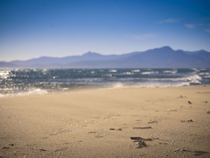 Una spiaggia con impronte e una catena montuosa sullo sfondo.