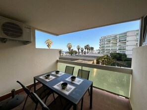 Ein Balkon mit Esstisch, Stühlen und einer Klimaanlage.