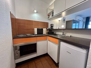 Una cucina compatta con forno a microonde, fornello, forno e lavastoviglie.
