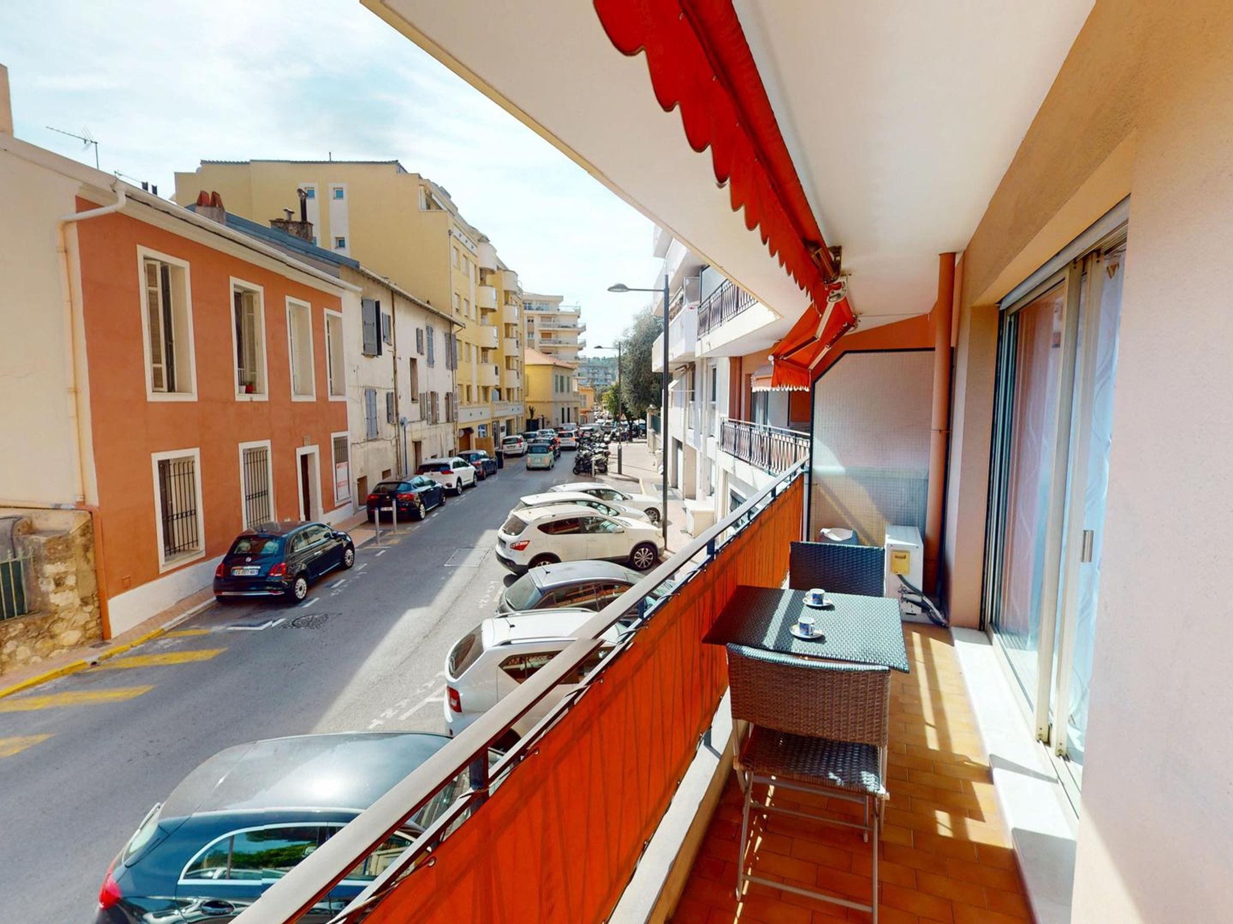 A balcony with a view of parked cars and buildings.