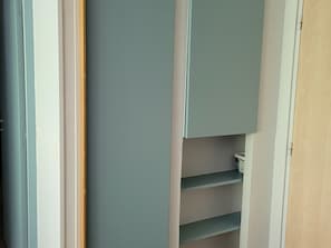 Ein Zimmer mit integriertem Kleiderschrank, einer Tür und einem Regalsystem.