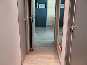 A hallway with a wooden floor leading to a room with a bed and a window. - Spacious apartment near slopes - 8 guests (Flaine)