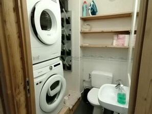 Ein kleines Badezimmer mit Waschmaschine, Toilette und Waschbecken.