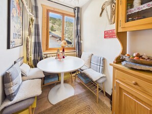 A cozy room with a round table, seating, a radiator, and a view of the outdoors. - Village center apartment, balcony - 4 guests (Les Gets)