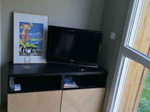 A flat-screen TV on a black entertainment unit with a framed magazine on top. - Luxury apartment near golf course - 4 guests (Barcelonnette)