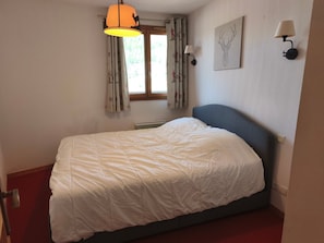 A bedroom with a bed, a window with curtains, a wall-mounted lamp, and a wall art piece. - Apartment - 6 guests, mountain view (Orcières Merlette)