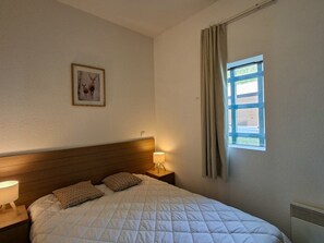 A bedroom with a bed, two bedside lamps, a nightstand, a framed picture on the wall, and a window with curtains. - Apartment at the slopes, parking - 6 guests (Flaine)
