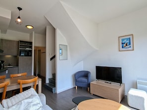 A modern living space with a dining area, a TV, and a staircase leading to a kitchen. - Apartment at the slopes, parking - 6 guests (Flaine)