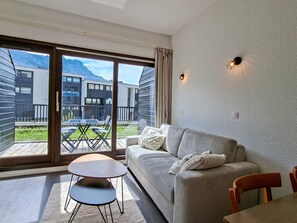 Una sala de estar moderna con un sofá, una mesita y vistas a la montaña a través de amplios ventanales.