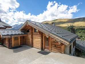 Een houten chalet met schuin dak, een houten deur en een klein terras.