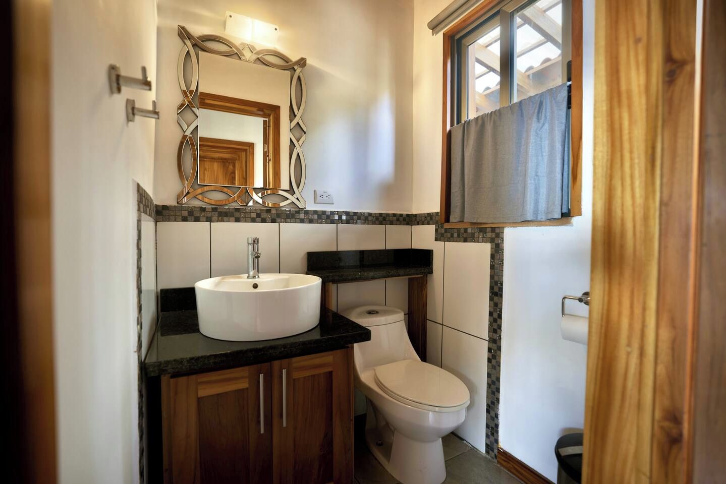 A bathroom with a white sink, a toilet, and a mirror with a decorative frame.
