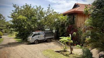 Een vrachtwagen geparkeerd voor een huis met een rode pannendak, omgeven door groen en een grindpad.