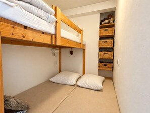 A bunk bed with a wooden frame, two pillows, and a small shelf with baskets. - Apartment, panoramic view - 4/5 guests (Chamrousse)