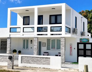 A modern two-story building with a white facade, multiple windows, and a sign indicating a poolside location. - Tranquil 3-bedroom house with AC in Río Grande (Río Grande)
