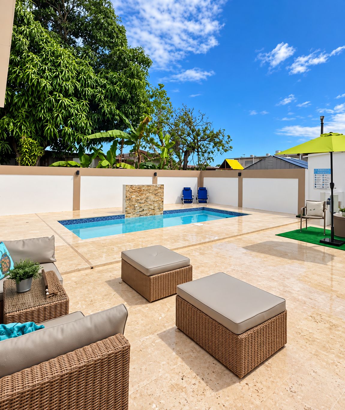 Un espace aménagé au bord de la piscine, avec une piscine, des meubles en osier et un parasol vert.