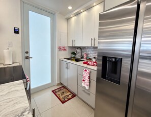 A modern kitchen with stainless steel appliances, white cabinetry, and a no-fume sign. - Tranquil 3-bedroom house with AC in Río Grande (Río Grande)
