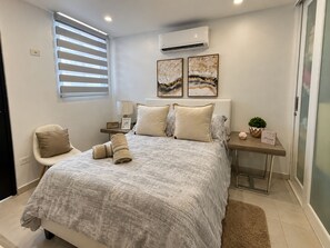 A bedroom with a bed, a chair, a nightstand, an air conditioner, and artwork on the wall. - Tranquil 3-bedroom house with AC in Río Grande (Río Grande)