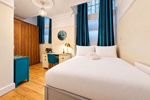 Hotellihuone, jossa on suuri sänky, työpöytä, tuoli, vaatekaappi ja näkymä ulos.
