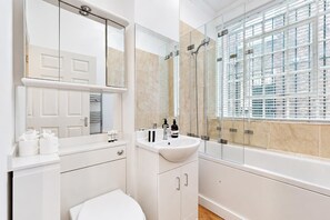 Ein modernes Badezimmer mit einem weißen Waschbecken, Spiegel und WC.