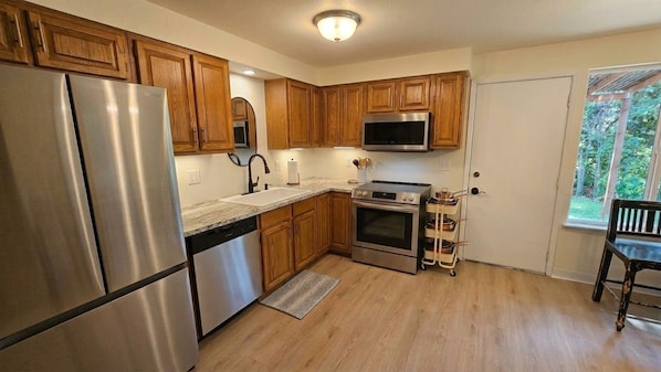 A kitchen with wooden cabinets, stainless steel appliances, a microwave, and a window with a view. - Boise home with private covered patio, lots of amenities, and amazing location (Boise)