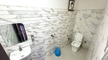 A bathroom with a marble backsplash, a sink, a toilet, and a mirror.