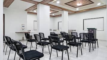 A conference room with black chairs arranged in rows, a whiteboard, and a water dispenser.