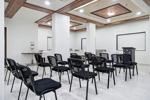 Un salón de conferencias con sillas negras dispuestas en filas, una pizarra y un dispensador de agua.