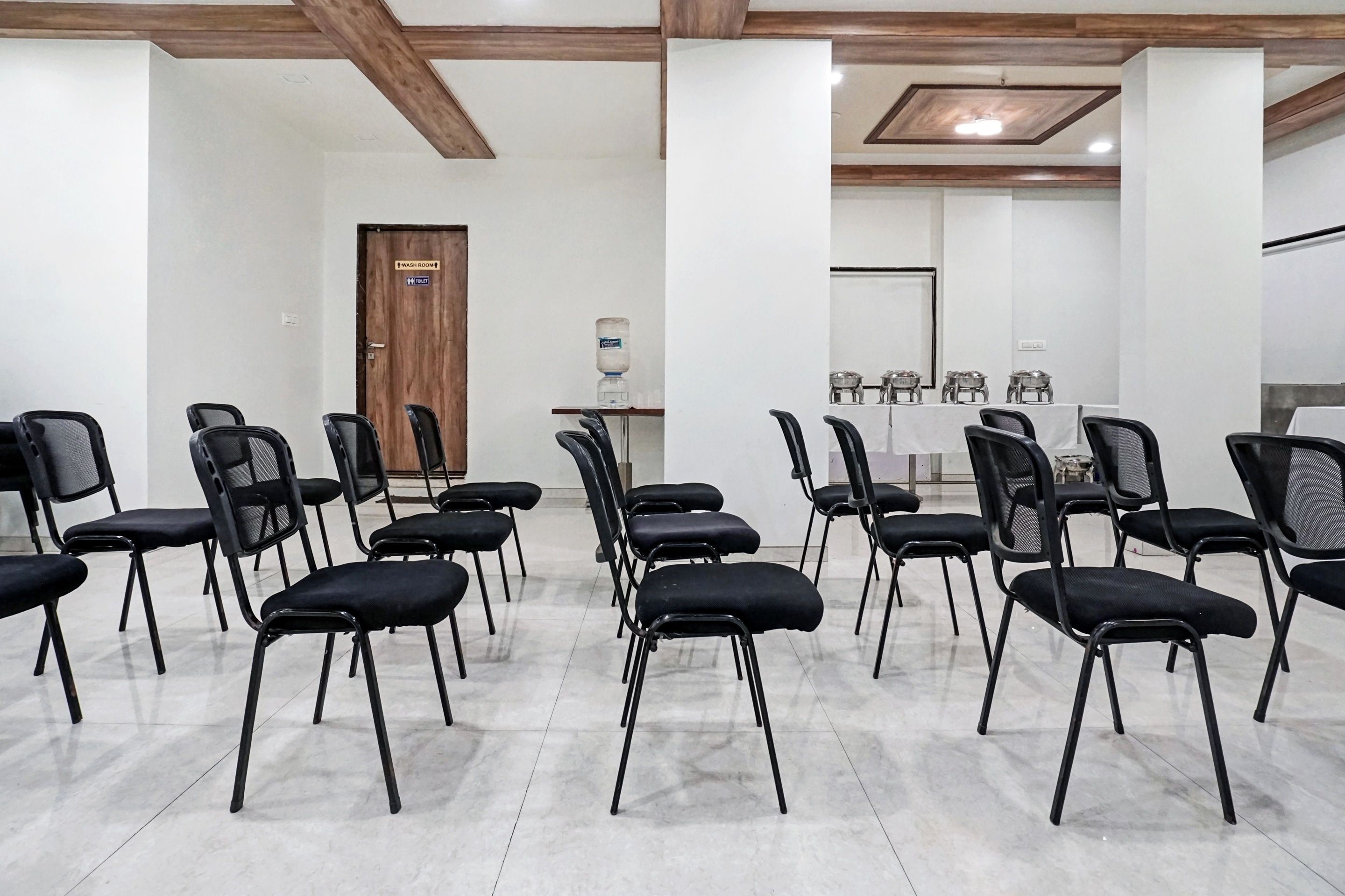 A conference room with rows of black chairs, a water dispenser, and a table with glassware.