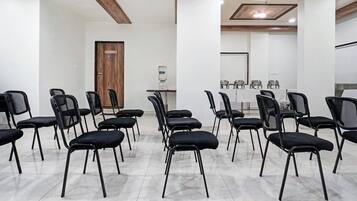 A conference room with rows of black chairs, a water dispenser, and a table with glassware.